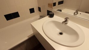 A bathroom with a white sink, a mirror, and a bathtub.