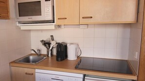 A compact kitchen with a microwave, coffee maker, and Bosch dishwasher.