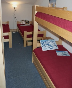 A dormitory room with bunk beds, a desk, and a lamp.