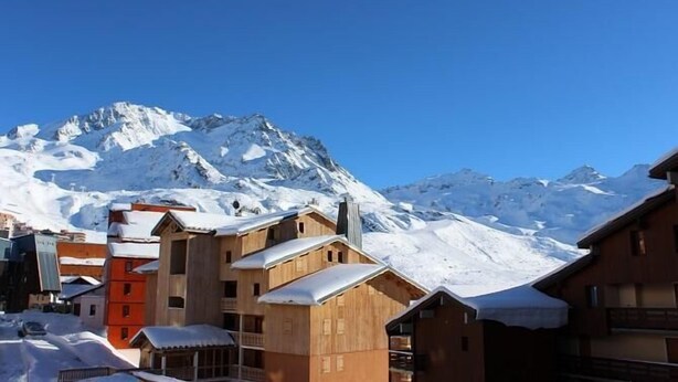 A snow-covered mountain with wooden buildings in the foreground.