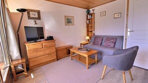 A cozy living room with a wooden dresser, a television, a sofa, and a lamp. - 200m from resort center, 2nd floor, view mountain, balcony, tv, 35m², Peisey-Vallandry (Landry)
