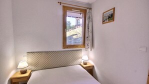 A bedroom with a bed, two bedside lamps, a window with a view, and a framed picture on the wall. - 200m from resort center, 2nd floor, view mountain, balcony, tv, 35m², Peisey-Vallandry (Landry)