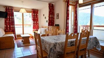 Une pièce confortable avec une table à manger, des chaises, un canapé et un téléviseur.
