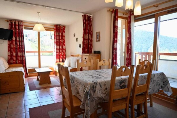 Una habitación acogedora con una mesa de comedor, sillas, un sofá y un televisor.