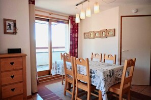 A dining area with a table set for four, wooden chairs, a wooden dresser with heart-shaped handles, and a sliding glass door leading to an outdoor balcony. - 100m from resort center, 1st floor, terrace, tv, 50m², Peisey-Vallandry (Landry)