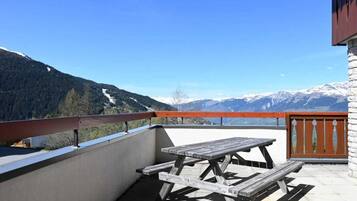 Une table de pique-nique en bois sur un balcon avec vue sur la montagne.