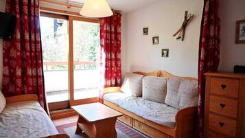 A cozy room with a bed, a sofa, a wooden dresser, and a table.