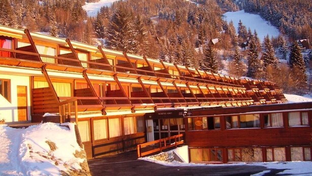 A wooden building with a sloped roof, likely a lodge or cabin, set against a snowy mountain backdrop. - 150m from resort center, 1st floor, balcony, parking, tv, 35m², Les Arcs (Bourg-Saint-Maurice)