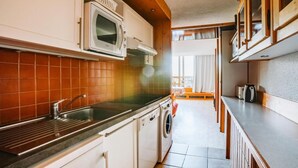 A compact kitchen with a microwave, sink, and washing machine. - 150m from resort center, 1st floor, balcony, parking, tv, 35m², Les Arcs (Bourg-Saint-Maurice)