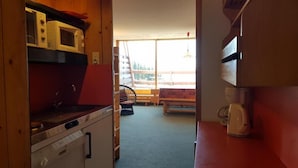 Een kleine keuken met een magnetron, koffiezetapparaat en uitzicht op het buitenterrein.