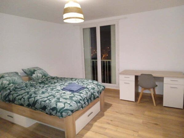A bedroom with a bed, a desk, and a chair.