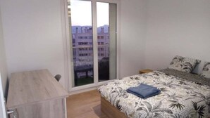 Ein Schlafzimmer mit Bett, einem Holztisch und einer Schiebetür zu einem Balkon.