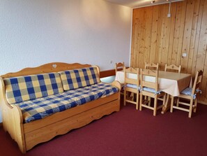 A wooden sofa with a checkered blanket, a wooden dining table with chairs, and a wooden wall panel. - 150m from resort center, 2nd floor, balcony, tv, 42m², Les Arcs (Les Arcs)