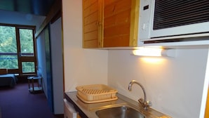 A compact kitchen with a stainless steel sink, wooden cabinets, and a window overlooking a balcony. - 50m from ski slopes, 4th floor, view forest, balcony, tv, 25m², Les Arcs (Les Arcs)