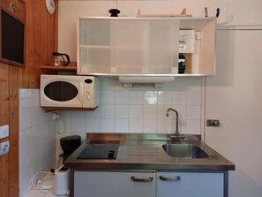 Eine kleine Küche mit Mikrowelle, Kaffeemaschine und Spüle.