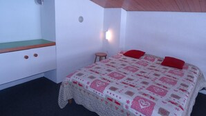 A bedroom with a bed, a small stool, a wooden bench, and a white wall with a light fixture. - Ski-in/ski-out & foot of the slopes, 2nd floor, view ski slopes, balcony, tv, 50m², Les Arcs (Les Arcs)