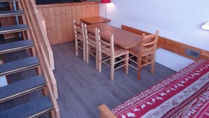 A wooden dining table with chairs, a red lamp, and a kitchen area with a microwave and TV. - Ski-in/ski-out & foot of the slopes, 2nd floor, view ski slopes, balcony, tv, 50m², Les Arcs (Les Arcs)