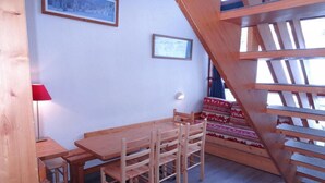 A wooden dining table with chairs, a red lamp, and a staircase with a wooden railing. - Ski-in/ski-out & foot of the slopes, 2nd floor, view ski slopes, balcony, tv, 50m², Les Arcs (Les Arcs)