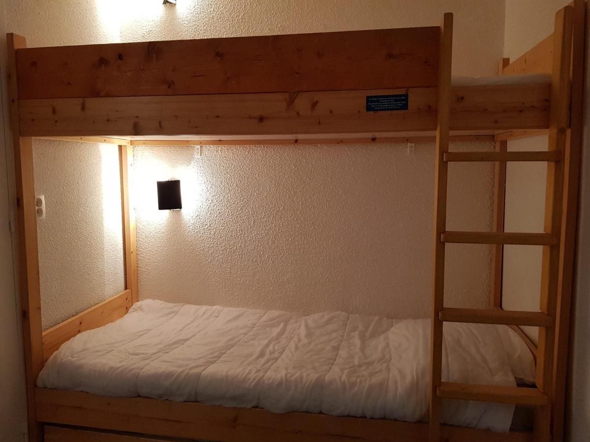 A bunk bed with a wooden frame, a single bed at the bottom, and a ladder on the right side.