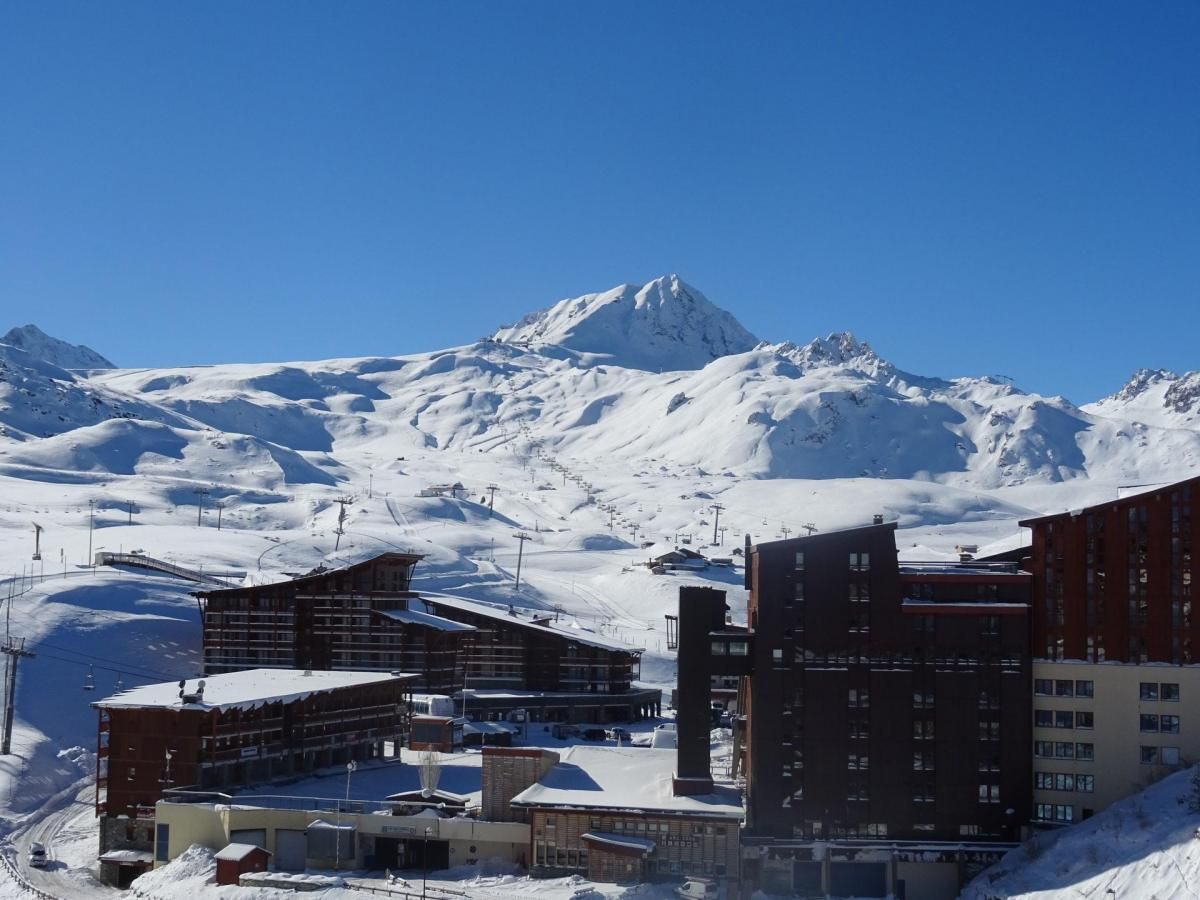 Ett snötäckt berg med en skidort i förgrunden, med moderna byggnader och skidliftar.