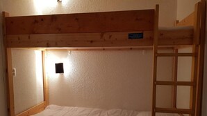 A bunk bed with a wooden frame, a small shelf, and a light fixture on the wall. - 200m from ski slopes, 11st floor, view mountain, balcony, tv, 28m², Les Arcs (Les Arcs)