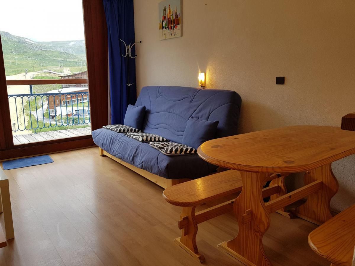 A room with a sofa, wooden table, and a view of a balcony with a railing.