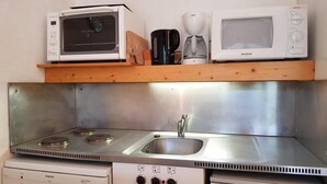 A compact kitchen with a stainless steel stove, a sink, and a microwave on a wooden shelf. - 200m from ski slopes, 11st floor, view mountain, balcony, tv, 28m², Les Arcs (Les Arcs)