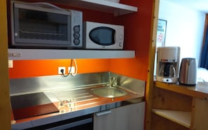 A compact kitchenette with a microwave, a coffee maker, and a sink.