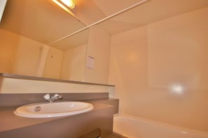 A bathroom with a white sink, mirror, and bathtub.