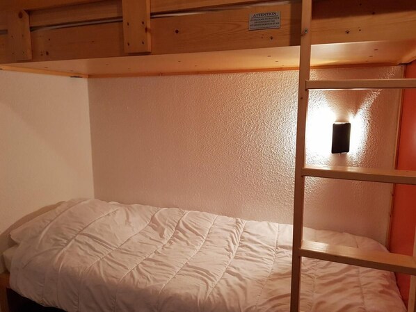 A bunk bed with a wooden frame and a white mattress.