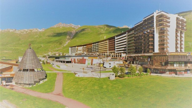 Et hotel med flere etager, en central gårdsplads og et bjerg i baggrunden.