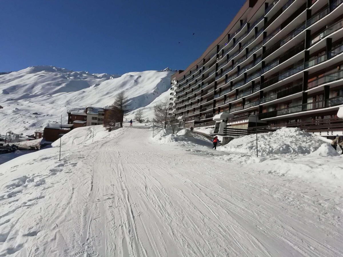 A snow-covered ski slope with a modern building on the right.