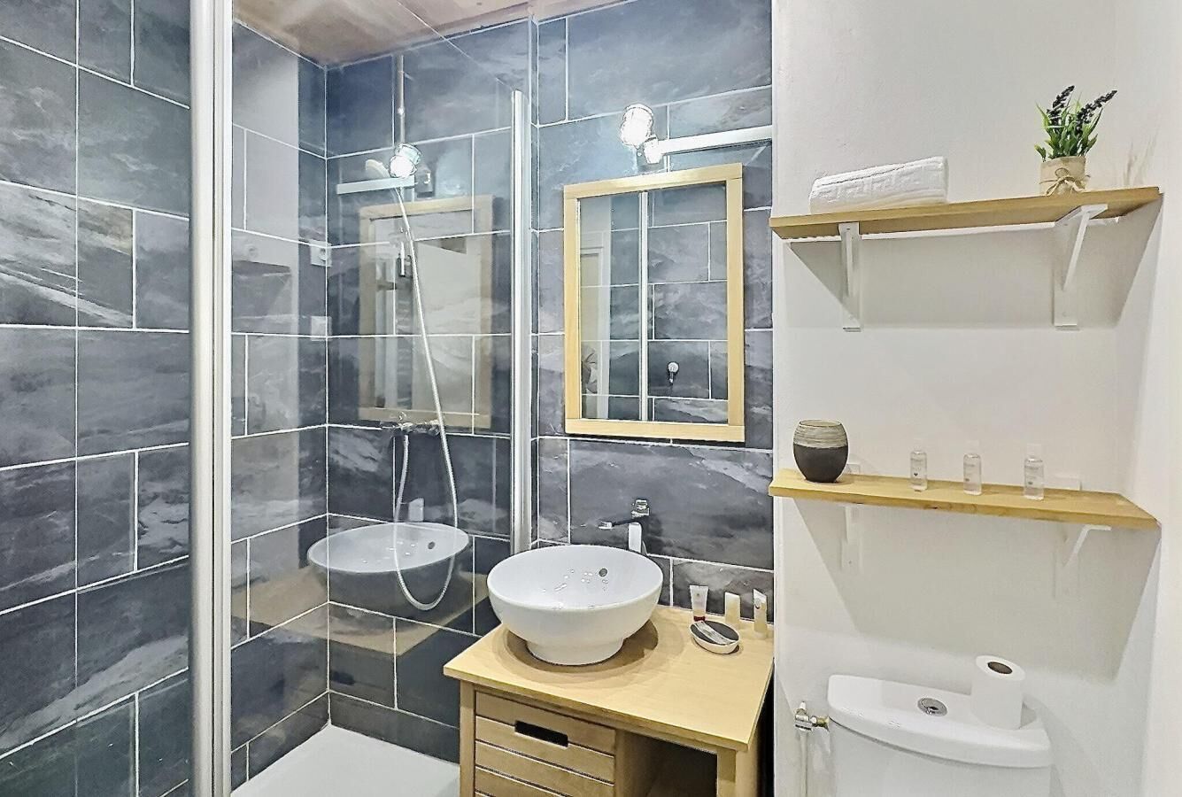 Ein modernes Badezimmer mit zwei Waschbecken, einer Duschkabine aus Glas und einem Spiegel über dem Waschbecken.
