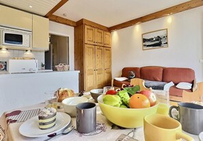 A dining area with a table set for breakfast, including fruits, pastries, and drinks.