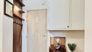 Ett rum med en träbänk, ett litet bord med en växt och en dörr med en träpanel.