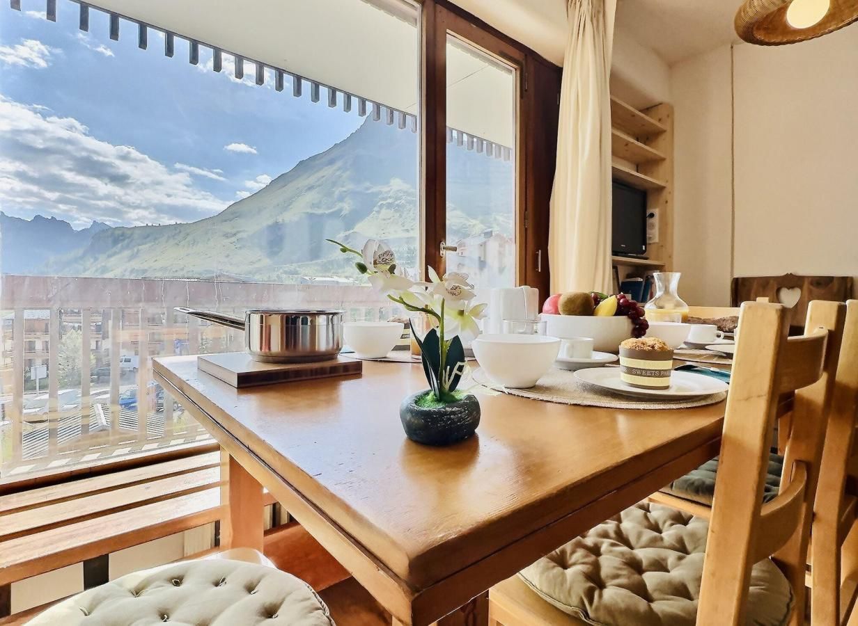 A dining area with a view of a mountain, a small vase with flowers, and a table set for two.