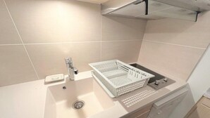 Ett modernt kök med en vit diskho, ett diskställ och en diskmaskin.