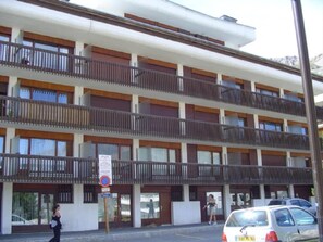 A multi-story hotel with balconies, a parking lot, and a pedestrian walkway.