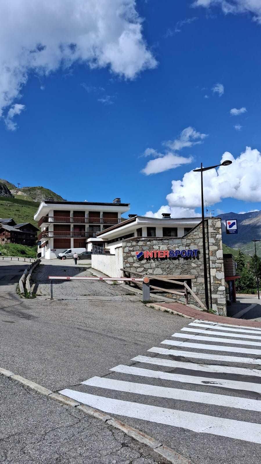 A building with a sign reading 'INTERSPORT' and a pedestrian crossing in front.