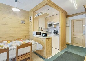 Una cocina compacta con una mesa de madera lista para el desayuno, un microondas y una cafetera.