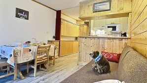A cozy room with a wooden interior, a dining area with a table set for two, and a pet sitting on a couch.