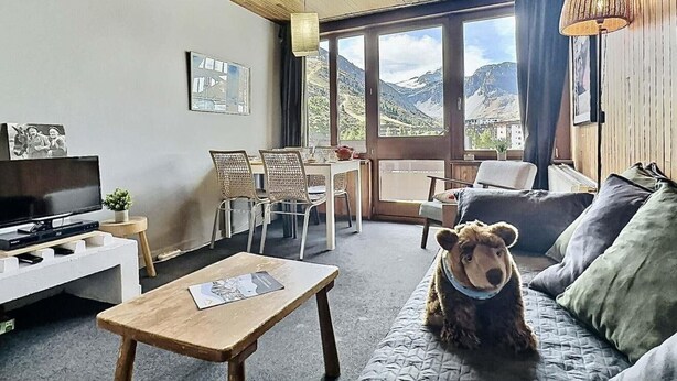 A cozy living room with a sofa, a coffee table, a TV, and a dog.