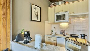 A compact kitchen with a microwave, toaster, and coffee maker on the counter.