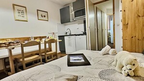 A compact bedroom with a bed, a small bedside table, a wooden chair, a kitchenette with a fridge, and a wooden wardrobe. - Ski-in/ski-out & foot of the slopes, 2nd floor, view street, balcony, tv, ski locker, 30m², Tignes (Tignes)