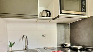 A modern kitchen with a stainless steel sink, a kettle, a microwave, and a stove. - Ski-in/ski-out & foot of the slopes, 2nd floor, view street, balcony, tv, ski locker, 30m², Tignes (Tignes)