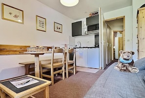 A compact room with a kitchenette, a dining area, and a bed.
