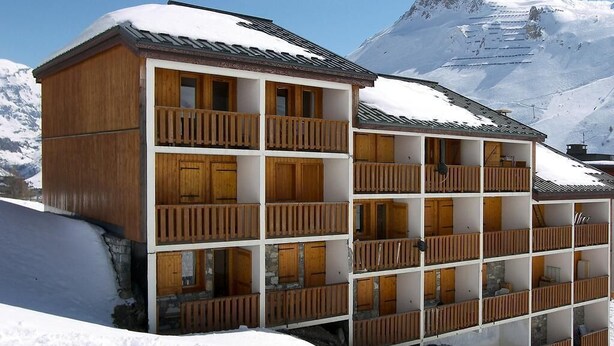 A multi-story wooden chalet with balconies, set against a snowy mountain backdrop. - Ski-in/ski-out & foot of the slopes, 2nd floor, view street, balcony, tv, ski locker, 30m², Tignes (Tignes)