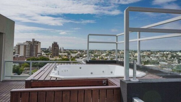 A rooftop terrace with a hot tub, wooden deck, and a city view. - LaGioconda aparthotel (Villa Maria)