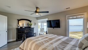Une chambre avec un lit, une commode, un téléviseur et une vue sur la mer.