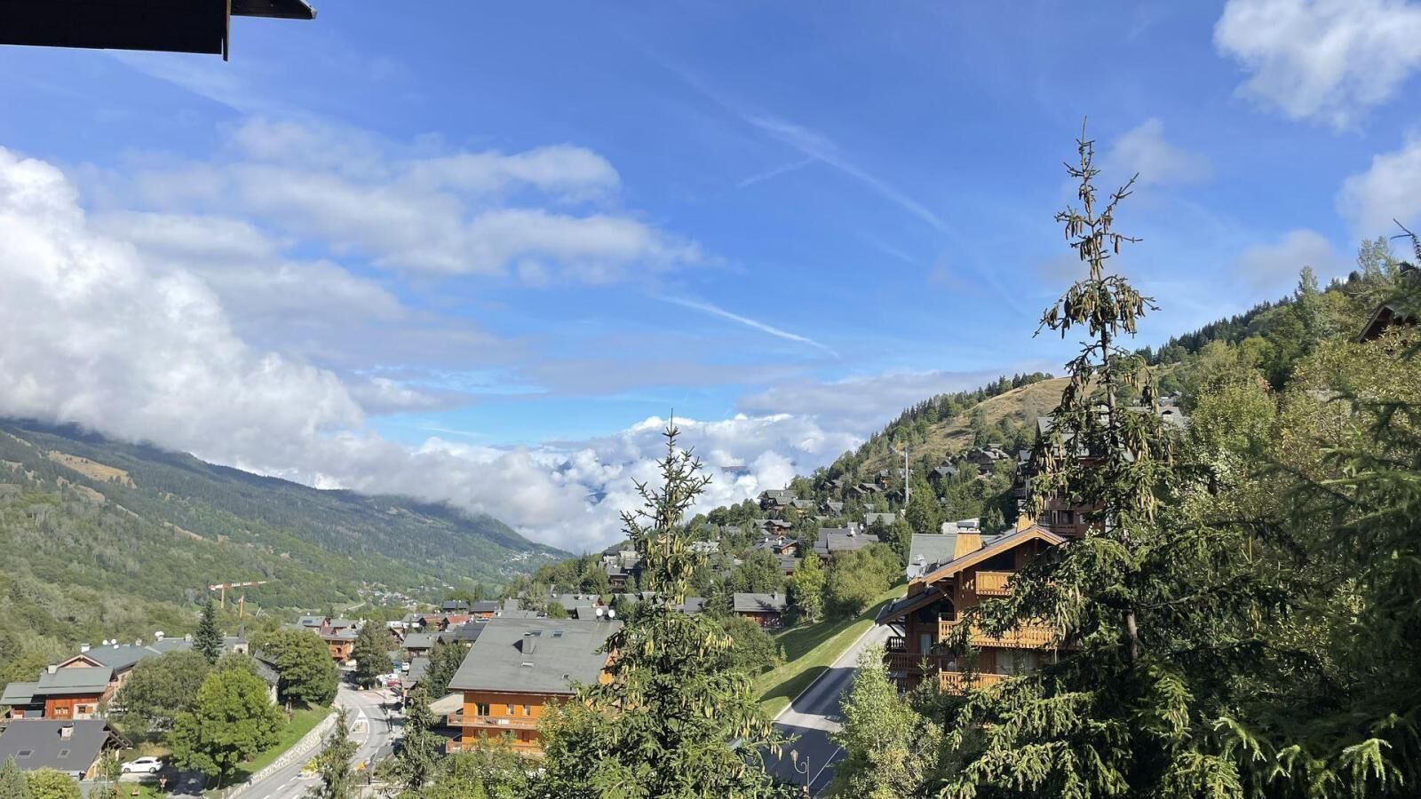 A mountain village with traditional wooden houses, a clear sky, and a valley below.